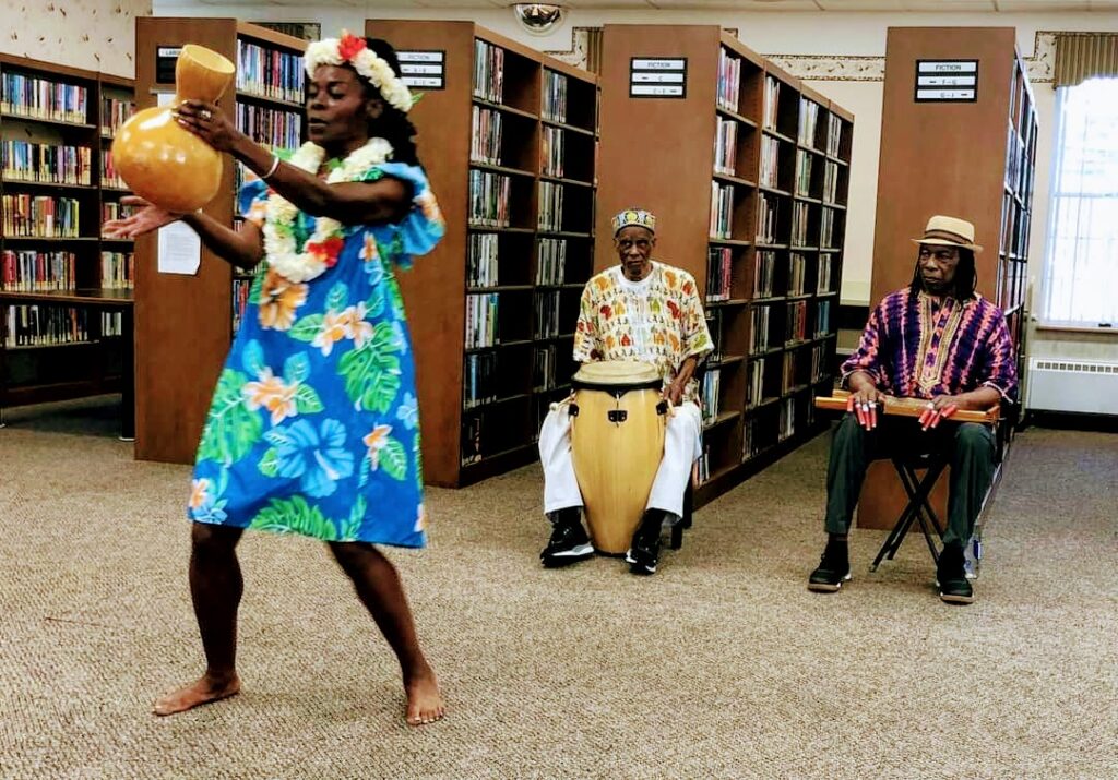 Shireen Dickson dances Pele with an ipu in a Polynesian inspired costume